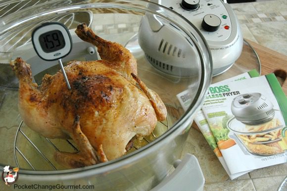 a whole chicken in a fryer with a thermometer