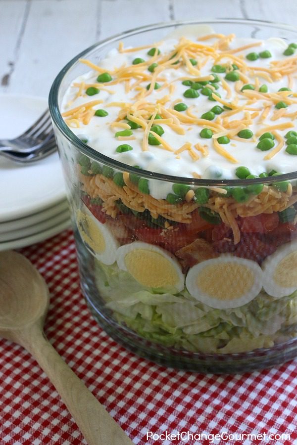 Heading to a potluck? Hosting a cookout? This Seven Layer Salad Recipe is a MUST make! A crowd-pleaser for sure! It's super easy to make, can be made ahead and feeds a crowd!