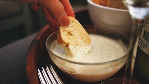 a person dipping the bread on the clam dip