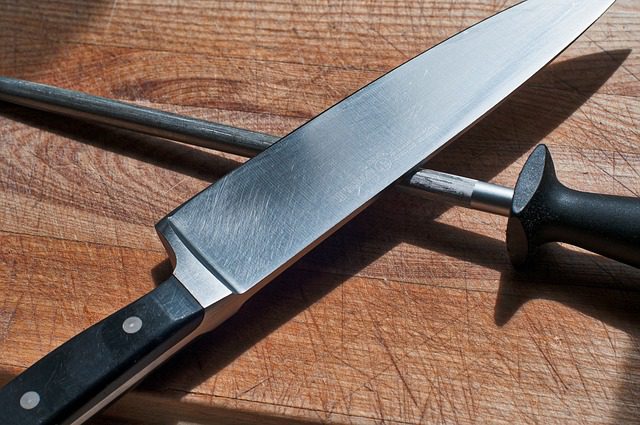 knife and sharpening steel on top of chopping board used to cut beef for the beef chow mein