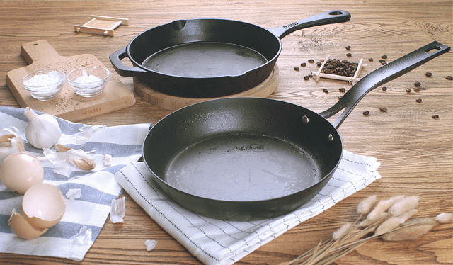 two cast iron pans being prepared for cooking