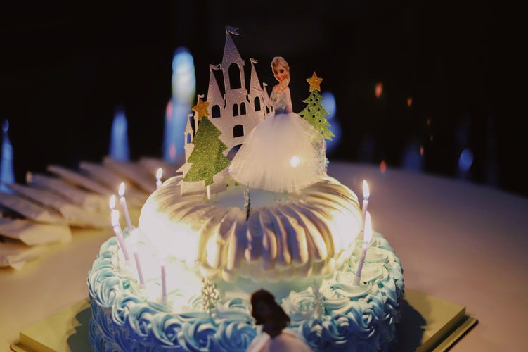 2-layer cake with lighted candles and Disney Frozen Queen Elsa cake topper