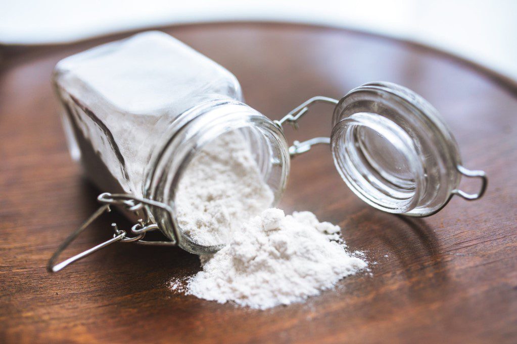 flour spilling on the table from a glass jar

