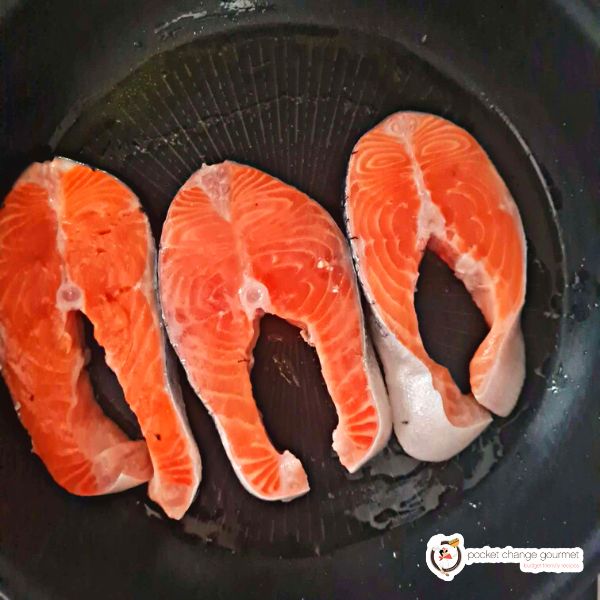 three pieces of fish being fried in a pan