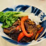 cooked Hunan beef, peppers, and bok choy in bowl with rice