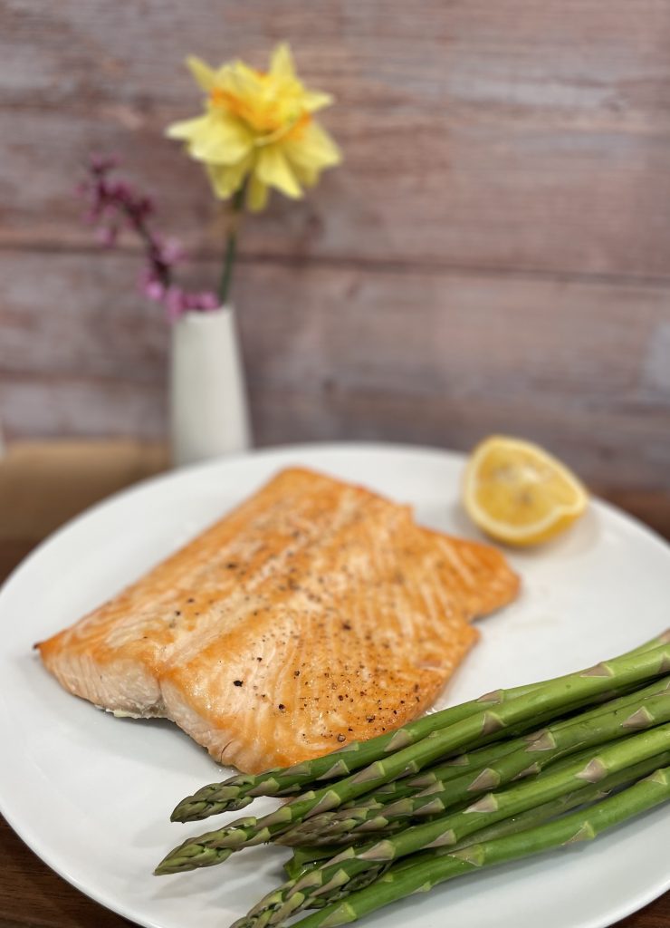 broiled salmon on a plate with asparagus and lemon