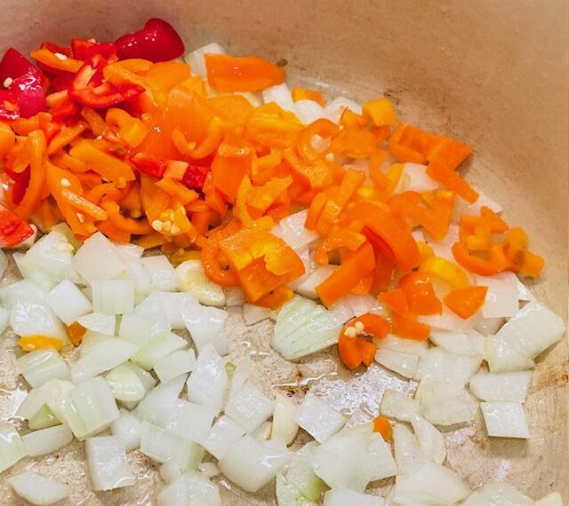 diced white onion and orange and red bell peppers in a pan