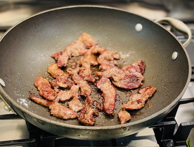 fried flank steak strips in pan