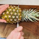 whole pineapple on cutting board with knife