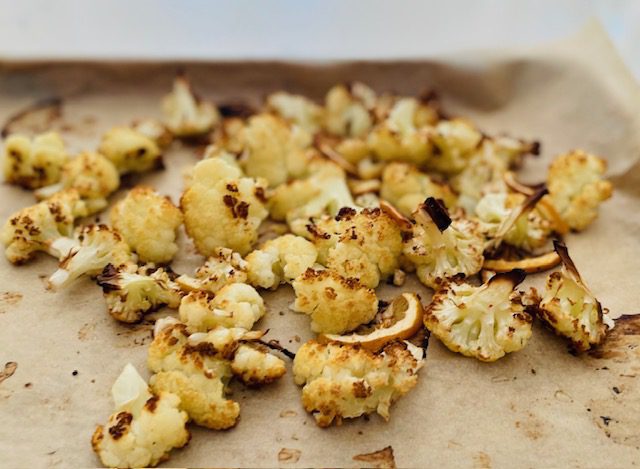 roasted cut cauliflower and sliced lemon on sheet pan with parchment