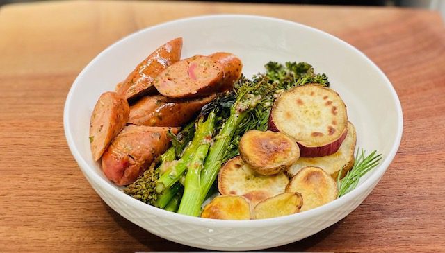 sliced roasted potatoes, broccolini, and sliced chicken sausage in white bowl.