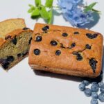 loaf of banana bread with blueberries sliced open on ceramic plate