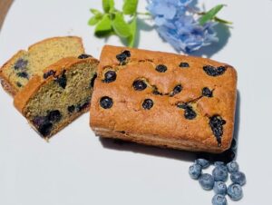 loaf of banana bread with blueberries sliced open on ceramic plate 