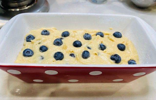 blueberries on top of loaf of gluten free banana bread before baking