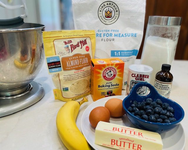 butter, eggs, banana, vanilla, baking soda, baking powder, almond flour, and sugar on kitchen counter