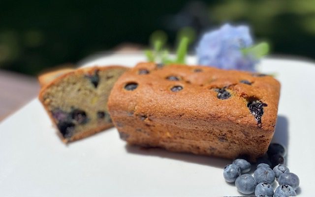 loaf of gluten free banana bread with blueberries sliced open on plate